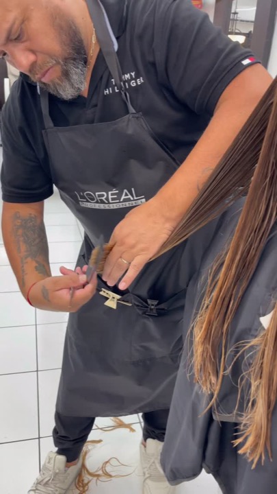 Stylist trimming a client's long brunette hair